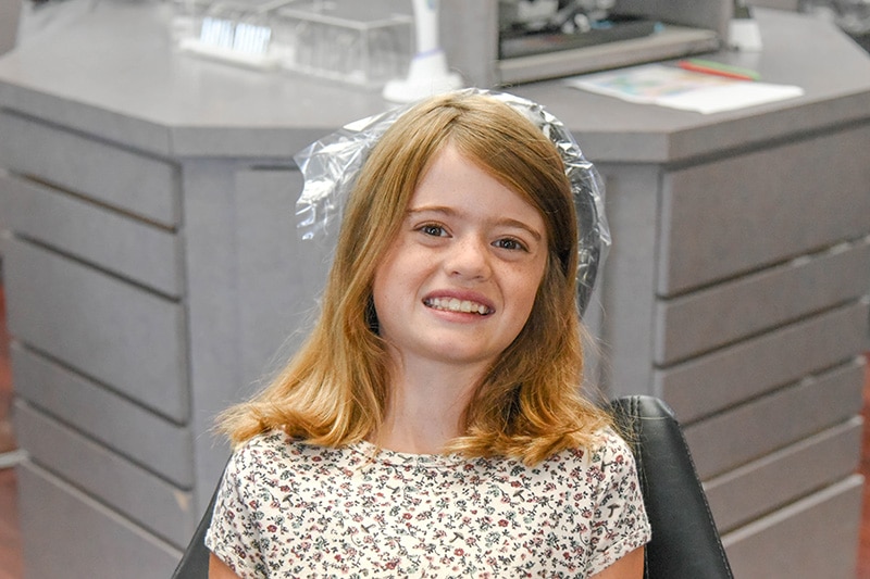 Early orthodontic patient smiling in dental chair