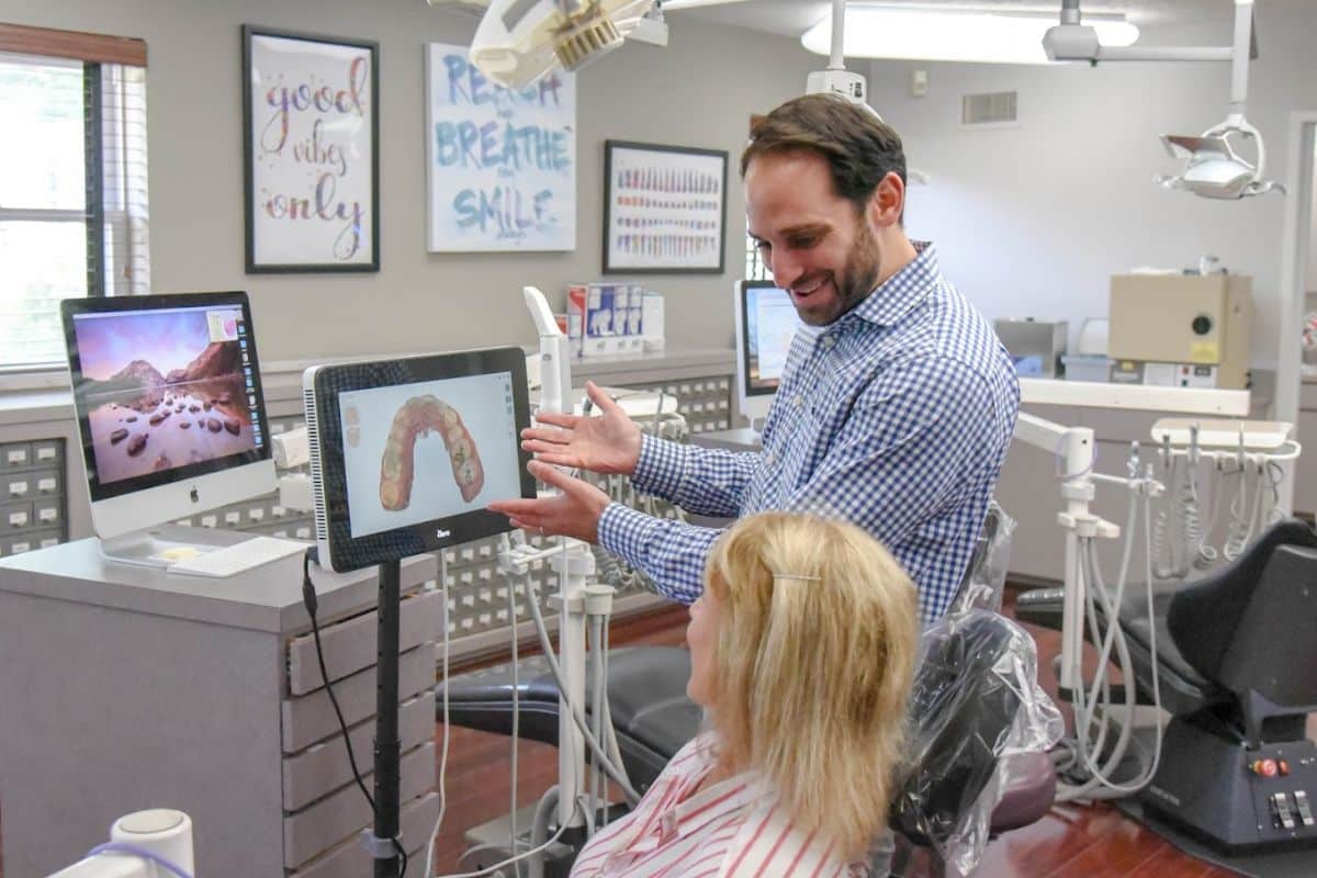 Smile-experience-orthodontics-near-hanover Orthodontic dentist working with a patient while pointing at a digital screen at smiles orthodontics near hanover